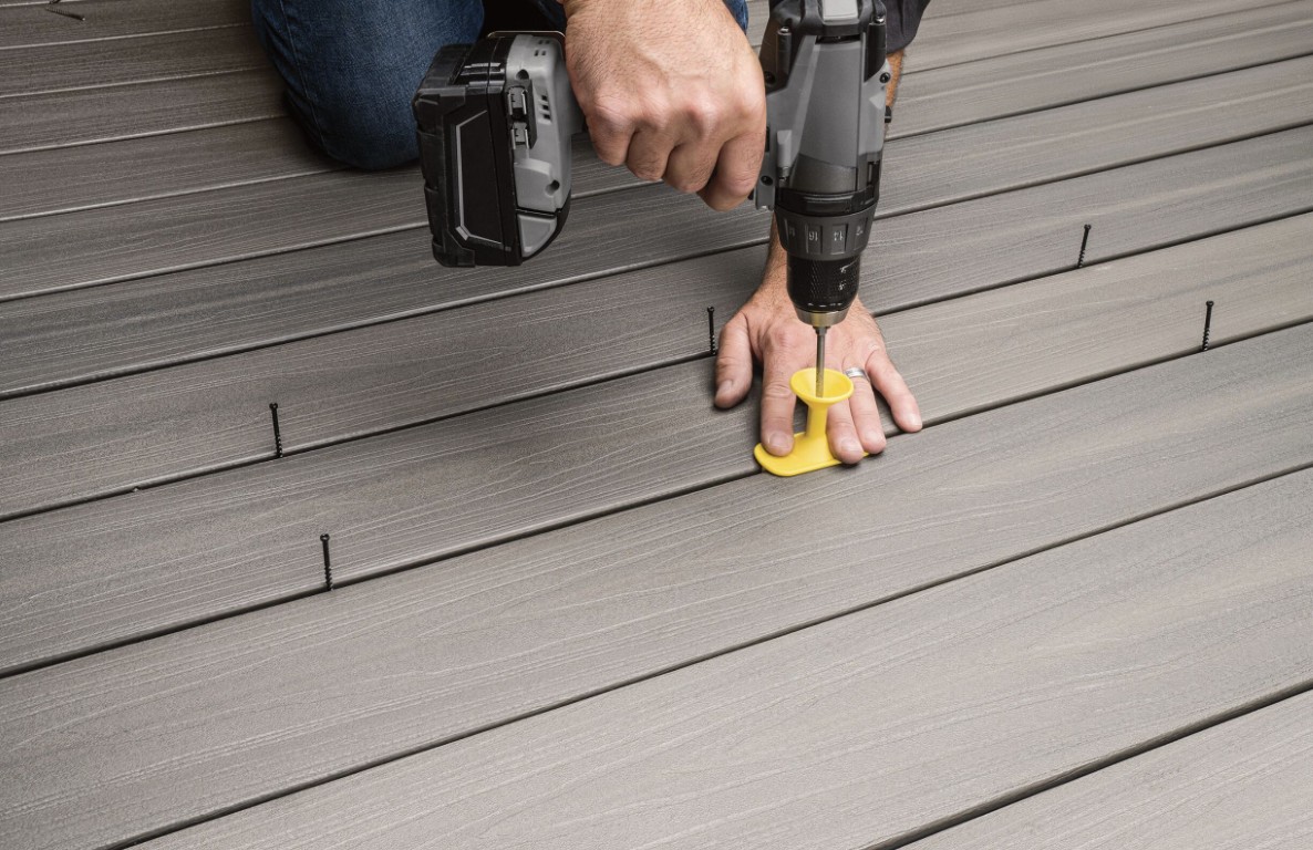 Professional installing composite deck boards with precision tools